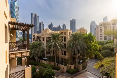 a building with palm trees in front of a city at Maison Privee - Stylish & Spacious Apartment in Downtown Dubai in Dubai
