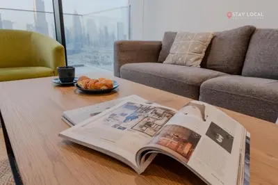 a newspaper on a coffee table with a book on it at Experience Iconic Burj Khalifa Views from Your Cozy Getaway with Pool in Dubai