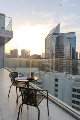 a balcony with a table and chairs and a view of a city at Experience Iconic Burj Khalifa Views from Your Cozy Getaway with Pool in Dubai