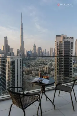 a table and chairs on a balcony with a view of a city at Experience Iconic Burj Khalifa Views from Your Cozy Getaway with Pool in Dubai