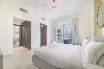 a white bedroom with a large bed and a large window at Luxurious 1-BR with Balcony & Views Business Bay in Dubai