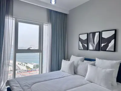 a bedroom with a bed and a large window at A Luxurious 2 Bedroom Emaar Beachfront Apartment in Palm Jumeirah in Dubai