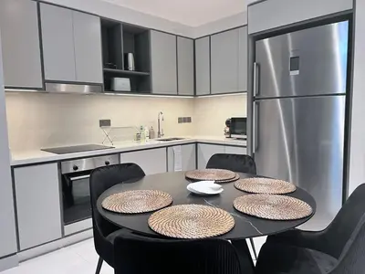 a kitchen with a table with chairs and a refrigerator at A Luxurious 2 Bedroom Emaar Beachfront Apartment in Palm Jumeirah in Dubai