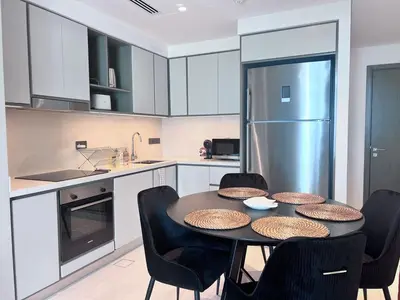 a kitchen with a table with chairs and a refrigerator at A Luxurious 2 Bedroom Emaar Beachfront Apartment in Palm Jumeirah in Dubai