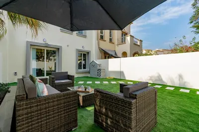 a patio with wicker chairs and an umbrella at White Sage Brand New 3BR Villa with Garden and Two Balconies in Dubai