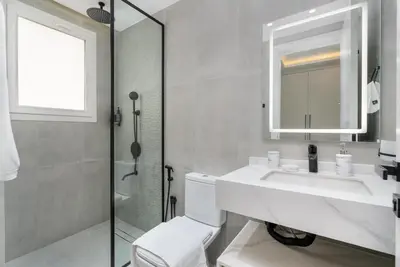 a white bathroom with a sink and a shower at White Sage Brand New 3BR Villa with Garden and Two Balconies in Dubai