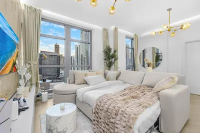 a living room with a couch and a large window at Walk to Dubai Mall 2BR Apartment with Balcony and Pool in Dubai
