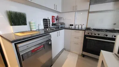 a kitchen with white cabinets and a stove top oven at Modern 2BR -5MIN to Metro & Festival Mall- 1211 in Dubai