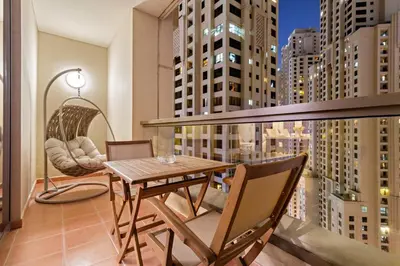 a balcony with a wooden table and chairs on a building at Luxe 2BR with Marina View in JBR and Walk to the Beach in Dubai