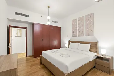 a bedroom with a large white bed and wooden floors at Luxe 2BR with Marina View in JBR and Walk to the Beach in Dubai