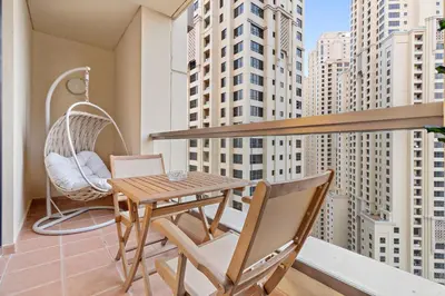 a balcony with a wooden table and chairs and a swing at Luxe 2BR with Marina View in JBR and Walk to the Beach in Dubai
