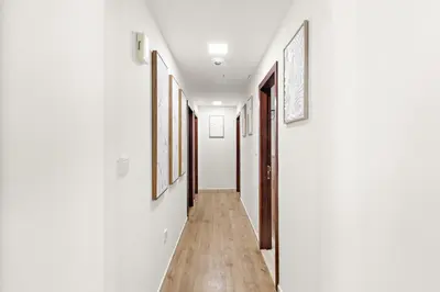 a hallway with white walls and wooden floors and paintings at Luxe 2BR with Marina View in JBR and Walk to the Beach in Dubai
