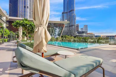 a patio with a chair and a umbrella and a pool at FIRST CLASS 2BR Incredible Burj Khalifa View in Dubai