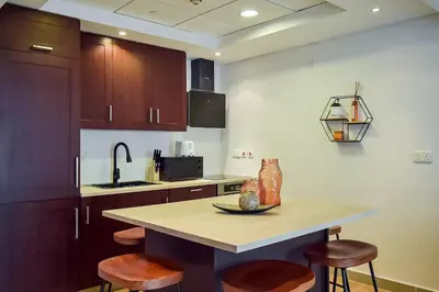 a kitchen with wooden cabinets and a table with chairs at Luxury Escapes - Modern 3BR Apt Stylish, Spacious and Comfortable in Dubai