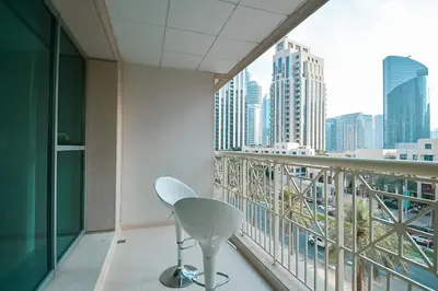 a white chair on a balcony with a city view at Luxury Escapes - Modern 3BR Apt Stylish, Spacious and Comfortable in Dubai