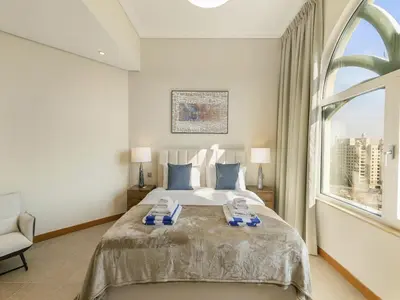 a bedroom with a large bed and a large window at Short-stay at Al Haseer - 4 Beds Palm Holiday Apt in Dubai