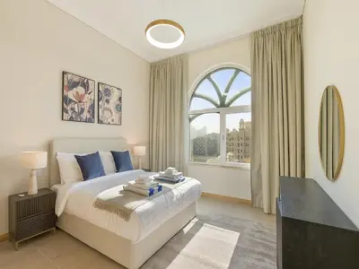 a bedroom with a bed and a large window at Short-stay at Al Haseer - 4 Beds Palm Holiday Apt in Dubai