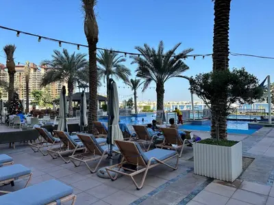 a group of chairs and umbrellas next to a pool at Short-stay at Al Haseer - 4 Beds Palm Holiday Apt in Dubai