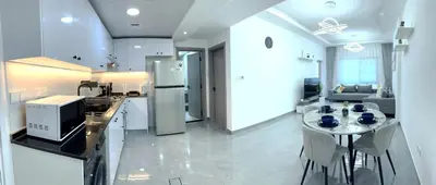 a kitchen and living room with a table and chairs at Dubai Marina - 1BHK Fancy Apartment in Dubai