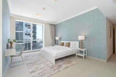 a bedroom with a large white bed and a window at Lavish 3BR Apartment with Pool Access in Al Bateen in Dubai
