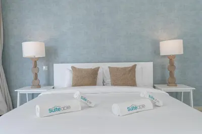 a white bed with two lamps and two pillows on it at Lavish 3BR Apartment with Pool Access in Al Bateen in Dubai