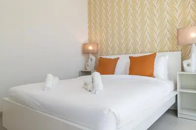 a white bed with orange pillows in a bedroom at Lavish 3BR Apartment with Pool Access in Al Bateen in Dubai