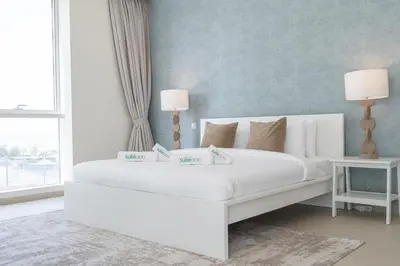 a white bed with two lamps in a bedroom at Lavish 3BR Apartment with Pool Access in Al Bateen in Dubai