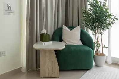 a green chair with a table in a living room at Kinfolk Homes - No 1 Family Stay, Partial Burj Khalifa Fountain View in Dubai