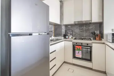 a kitchen with white cabinets and a refrigerator at Frank Porter - Nobles Tower in Dubai