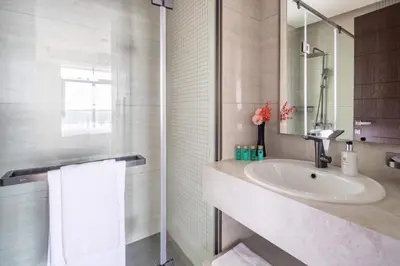 a white bathroom with a sink and a shower at Frank Porter - Nobles Tower in Dubai