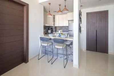 a kitchen with a bar with stools and a sink at Frank Porter - Nobles Tower in Dubai