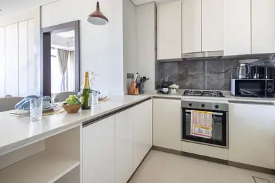 a kitchen with white cabinets and a stove top oven at Frank Porter - Nobles Tower in Dubai
