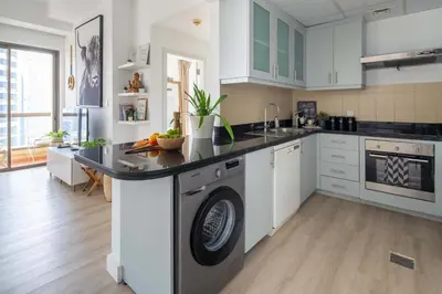 a kitchen with white cabinets and a washer at Frank Porter - Bahar 6 in Dubai