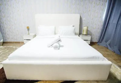a large white bed in a bedroom with blue curtains at High Class 1bhk Business bay Marasi Drive Dubai in Dubai