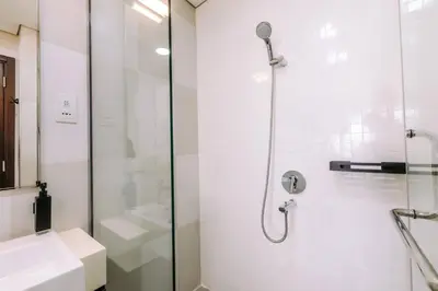 a white bathroom with a shower and a sink at Beachfront Bliss on the Palm Jumeirah in Dubai