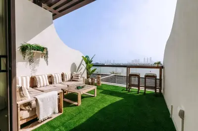 a balcony with a couch and green grass at Beachfront Bliss on the Palm Jumeirah in Dubai