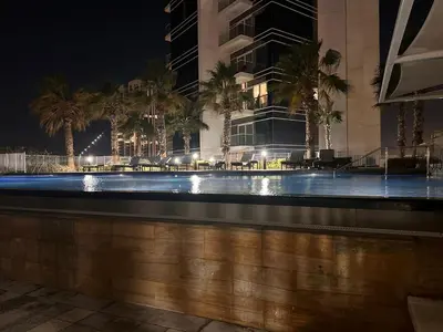 a swimming pool at night with palm trees and a building at Damac Hills in Dubai