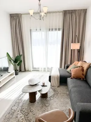 a living room with a couch and a table at Cozy 1 Bedroom Apartment in Dubai