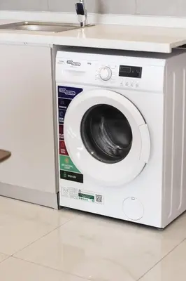 a white washing machine sitting under a counter at Cozy 1 Bedroom Apartment in Dubai