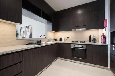 a kitchen with dark brown cabinets and a sink at High-Floor Luxe 2BR Stunning Burj Khalifa & Fountain Views Direct Dubai Mall Access in Dubai