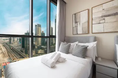a bedroom with a white bed with a large window at High-Floor Luxe 2BR Stunning Burj Khalifa & Fountain Views Direct Dubai Mall Access in Dubai