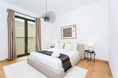 a white bedroom with a bed and a large window at Escape24 Luxury 2BR Sea View with Beach Access in La Mer in Dubai