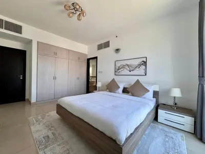 a bedroom with a large white bed and a chandelier at 2 Bed Apartment in La Riviera Tower, Dubai Marina near Metro and Mall, 12-min walk to JBR Beach! in Dubai