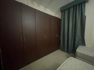 a bedroom with brown cabinets and a window at Room In Barsha Heights in Dubai