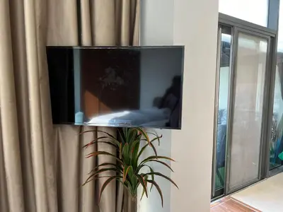 a flat screen tv on a wall with a plant at Jumeirah Village Circle JVC One bedroom Luxurious Apartment in Dubai