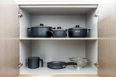 four pots and pans on a shelf in a kitchen at Luxurious 4BR, Burj Khalifa & full fountain view, Downtown Dubai in Dubai
