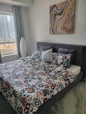 a bedroom with a bed with a floral comforter and a window at AHLAN Dubai Marina JBR in Dubai