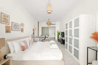 a white bedroom with a large bed and a living room at Silkhaus Offshore Studio in Palm Views East Tower in Dubai