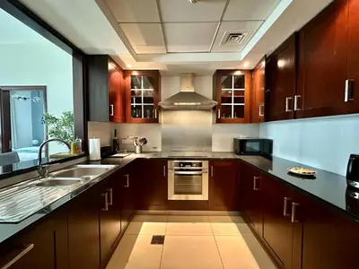 a kitchen with wooden cabinets and a sink and a stove at Silkhaus 1BR Downtown Heart in Emaar Tower in Dubai