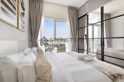 a bedroom with a large white bed with a large window at Bright 1BR at Collective Tower 1 Near Hills Mall in Dubai